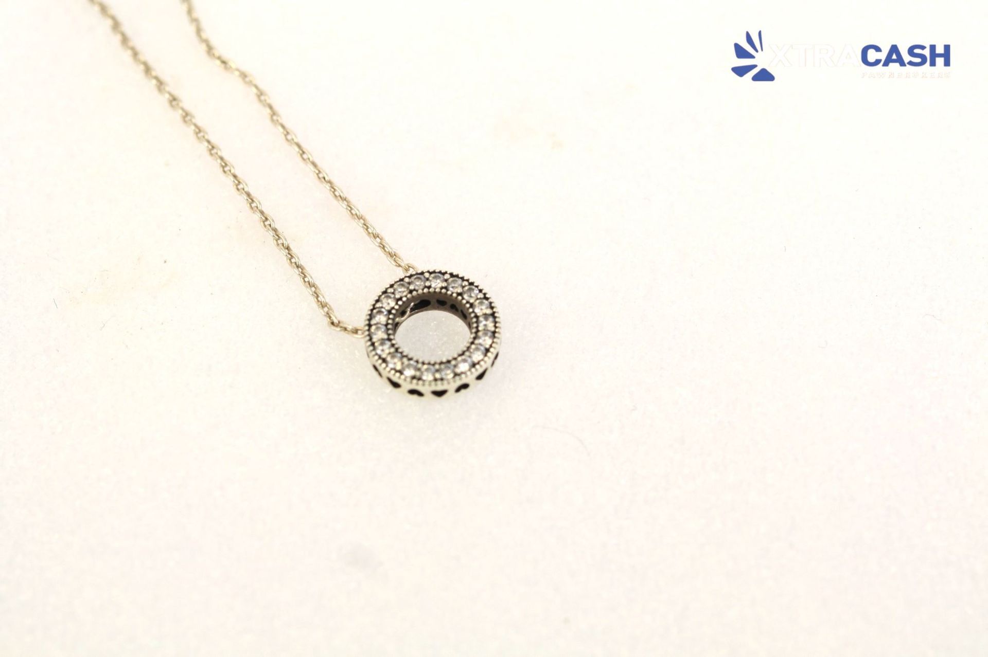 Gold necklace with a circular pendant on a white background