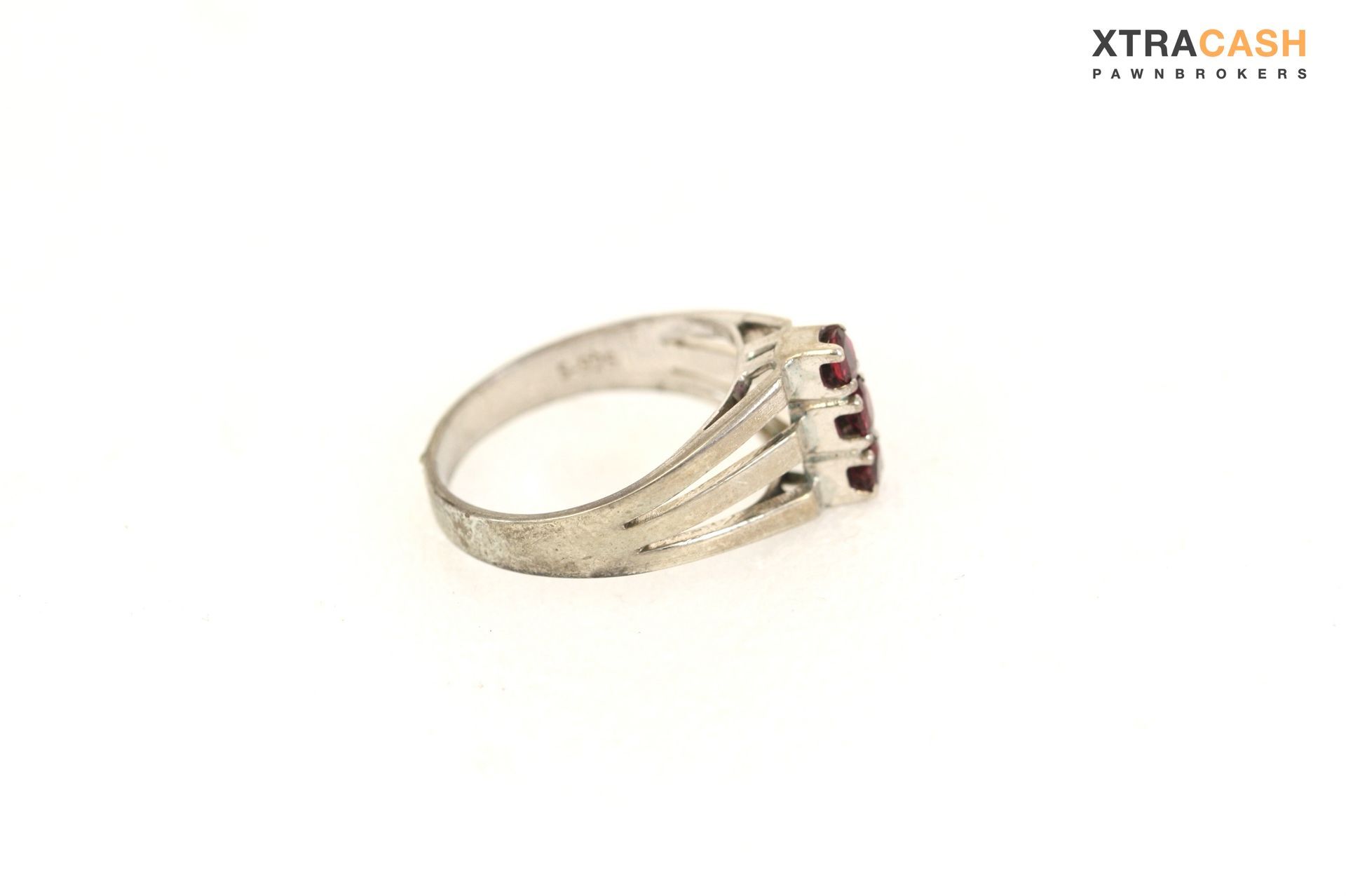 Gold ring with two red gemstones and a V-shaped silver accent on a white background