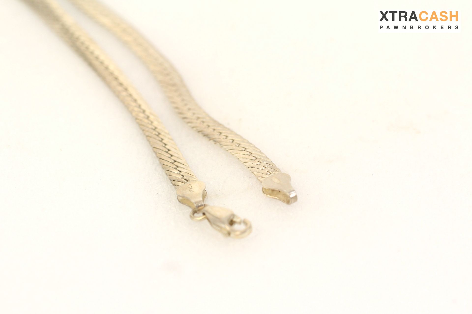 Silver chain necklace laid in a loop on a light background