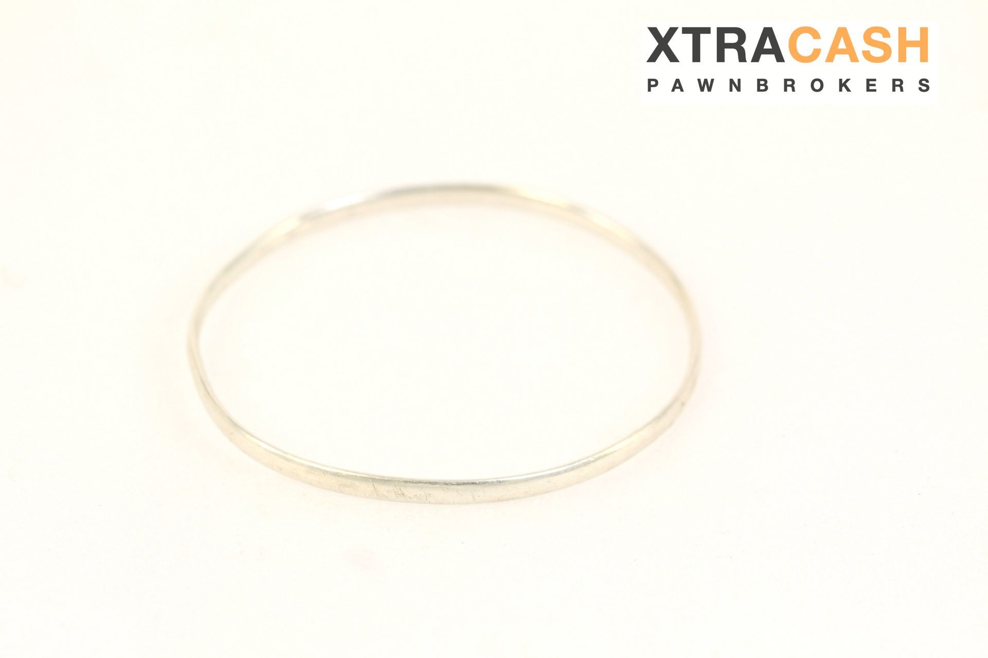 Thin gold bracelet or anklet on a white background with XtraCash Pawnshop logo
