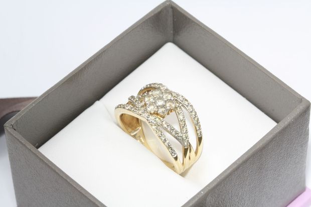 Gold ring with sparkling stones displayed in a gray jewelry box