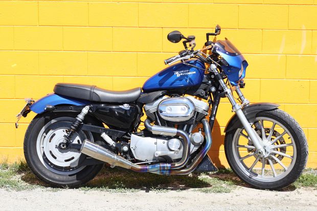 Blue motorcycle parked against a yellow brick wall