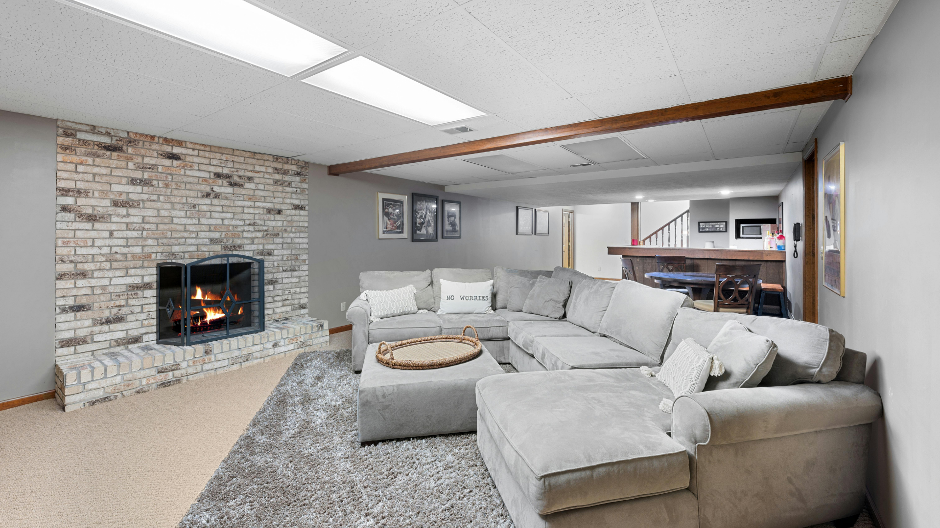 Living room with white couches, fireplace, and glass coffee table, light gray walls, and door to the outdoors.
