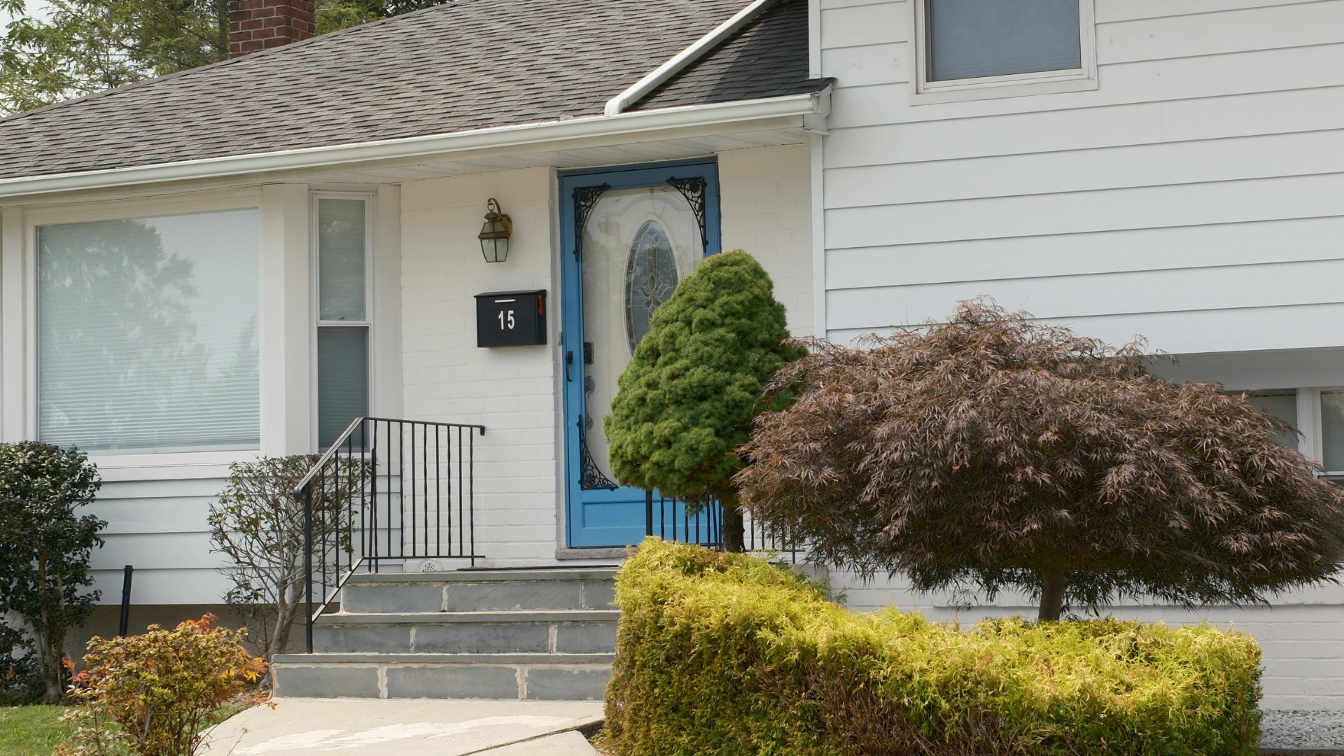 Suburban two-story house with beige siding, three-car garage, and driveway under a blue sky.