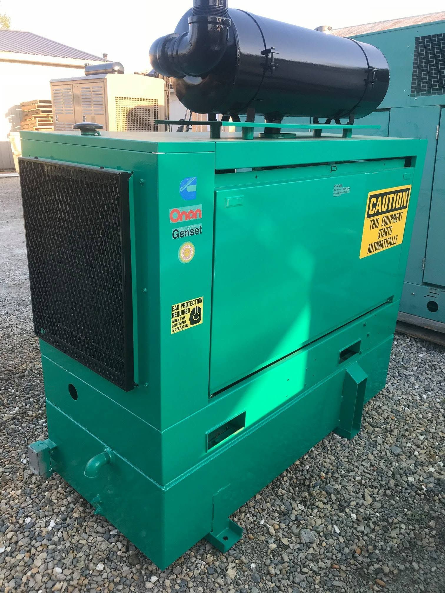 Green industrial generator on gravel with a black cylindrical tank mounted on top.