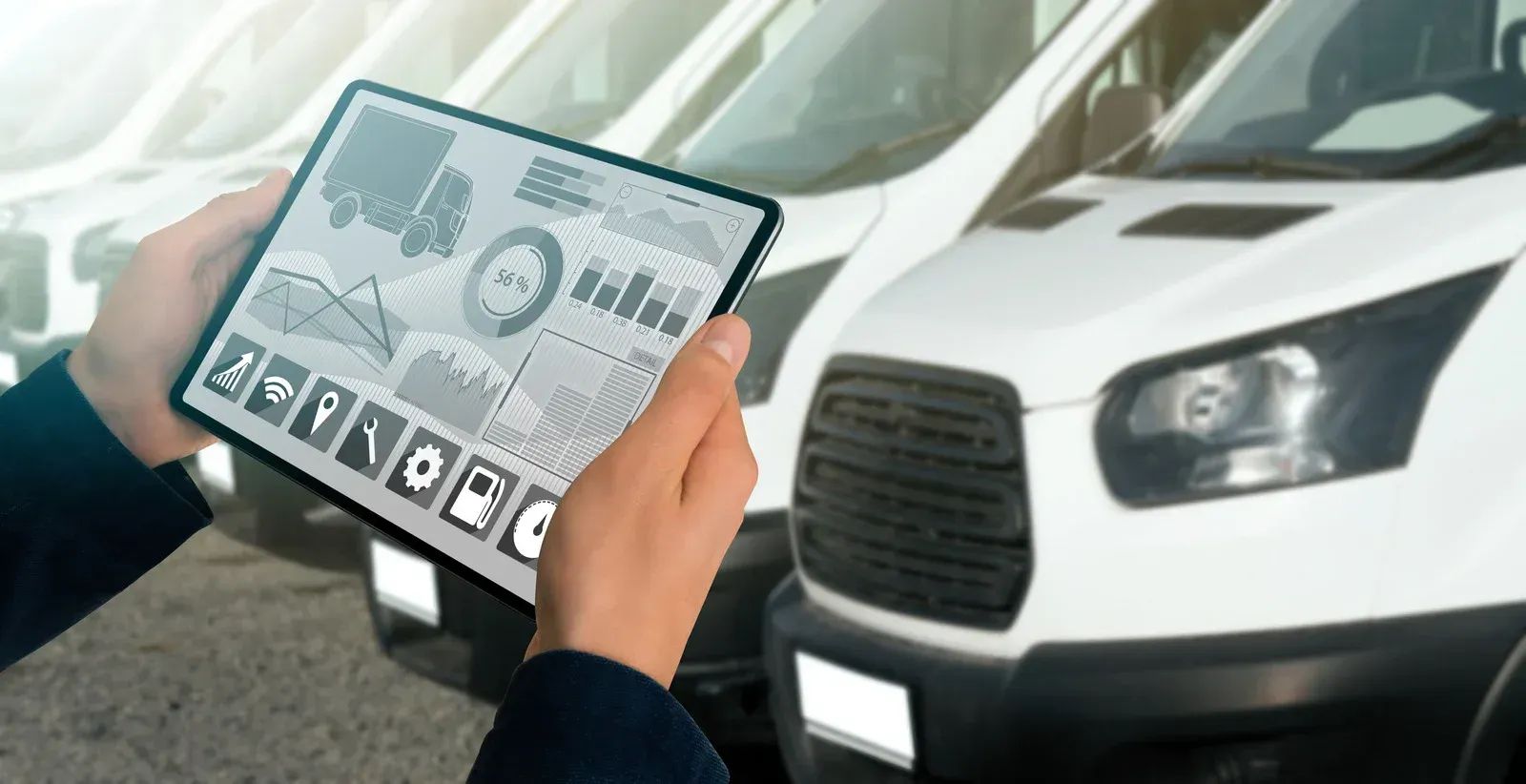 Hands holding a tablet with car diagnostics beside a white vehicle in a garage