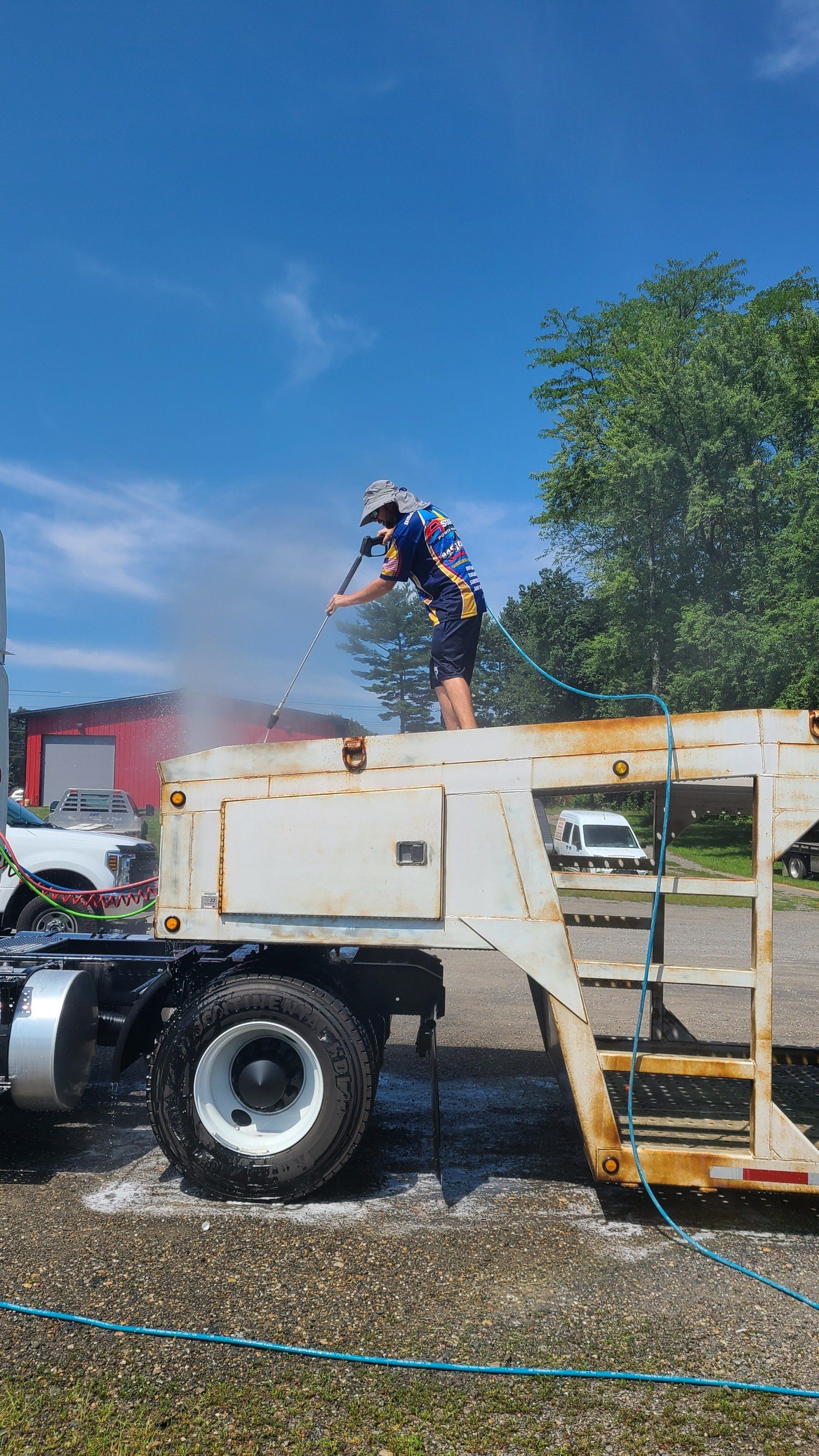 Person Pressure Washing A Rusty Trailer.