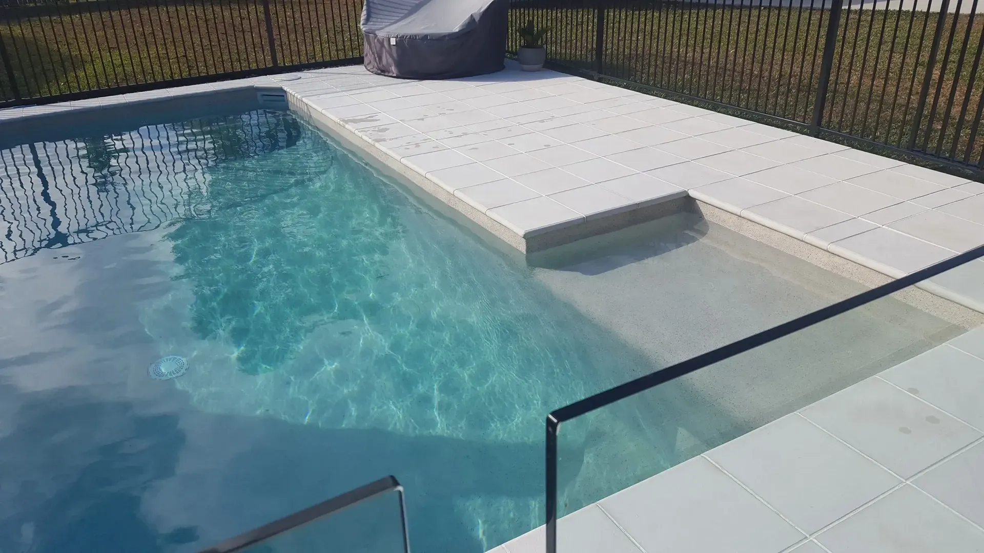 A Large Swimming Pool With A Glass Fence And Stairs Leading To It — Tropical North Swimming Pools 'n' Spas In Currajong, QLD
