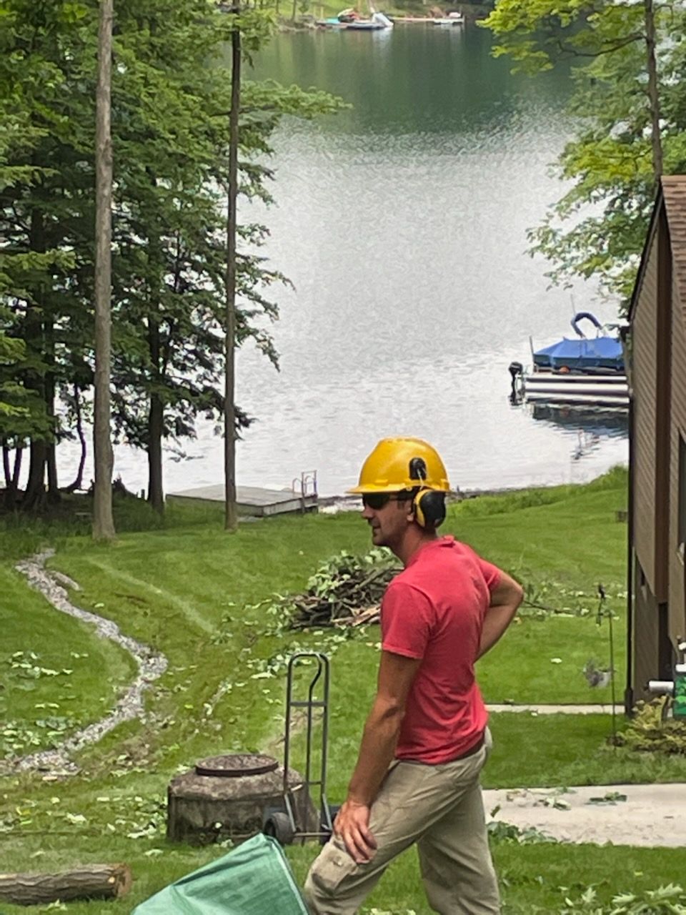 A man wearing a hard hat is standing in front of a lake.
