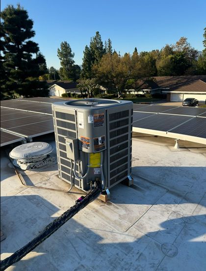 Outdoor rooftop HVAC unit with solar panels and trees in the background