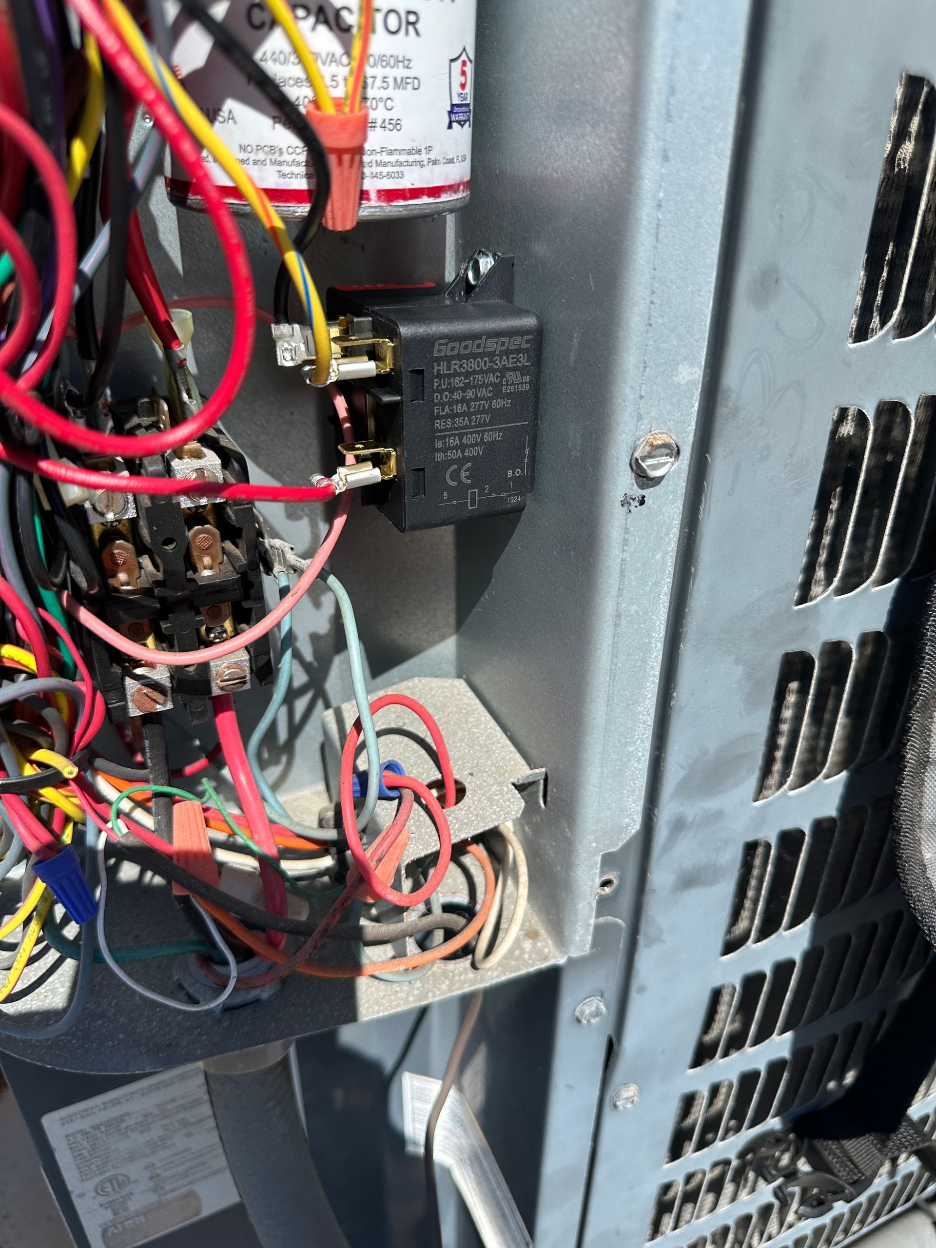 Open electrical control panel with tangled red, black, and blue wires and components inside a metal cabinet