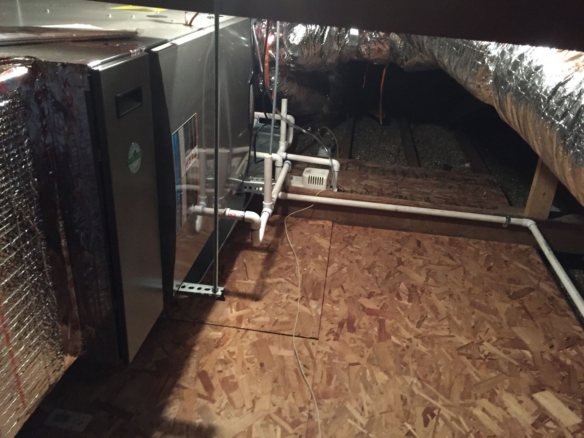 Attic crawlspace with insulation, exposed ductwork, and wooden flooring under low beams