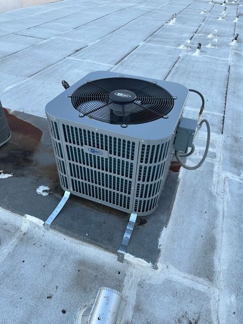 Outdoor air conditioning unit on a flat rooftop, with snow on the ground around it.