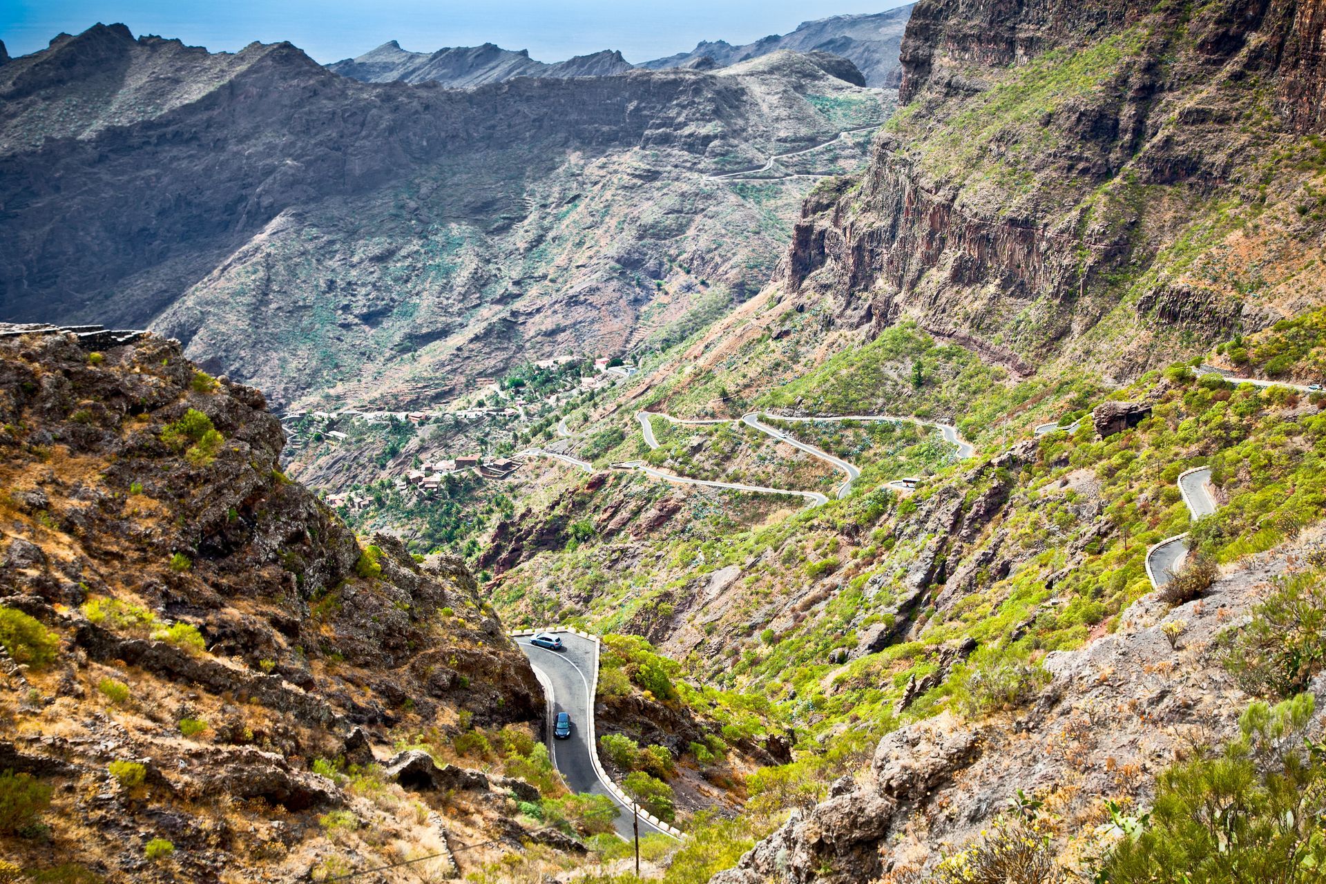 A car is driving down a winding road in the mountains.