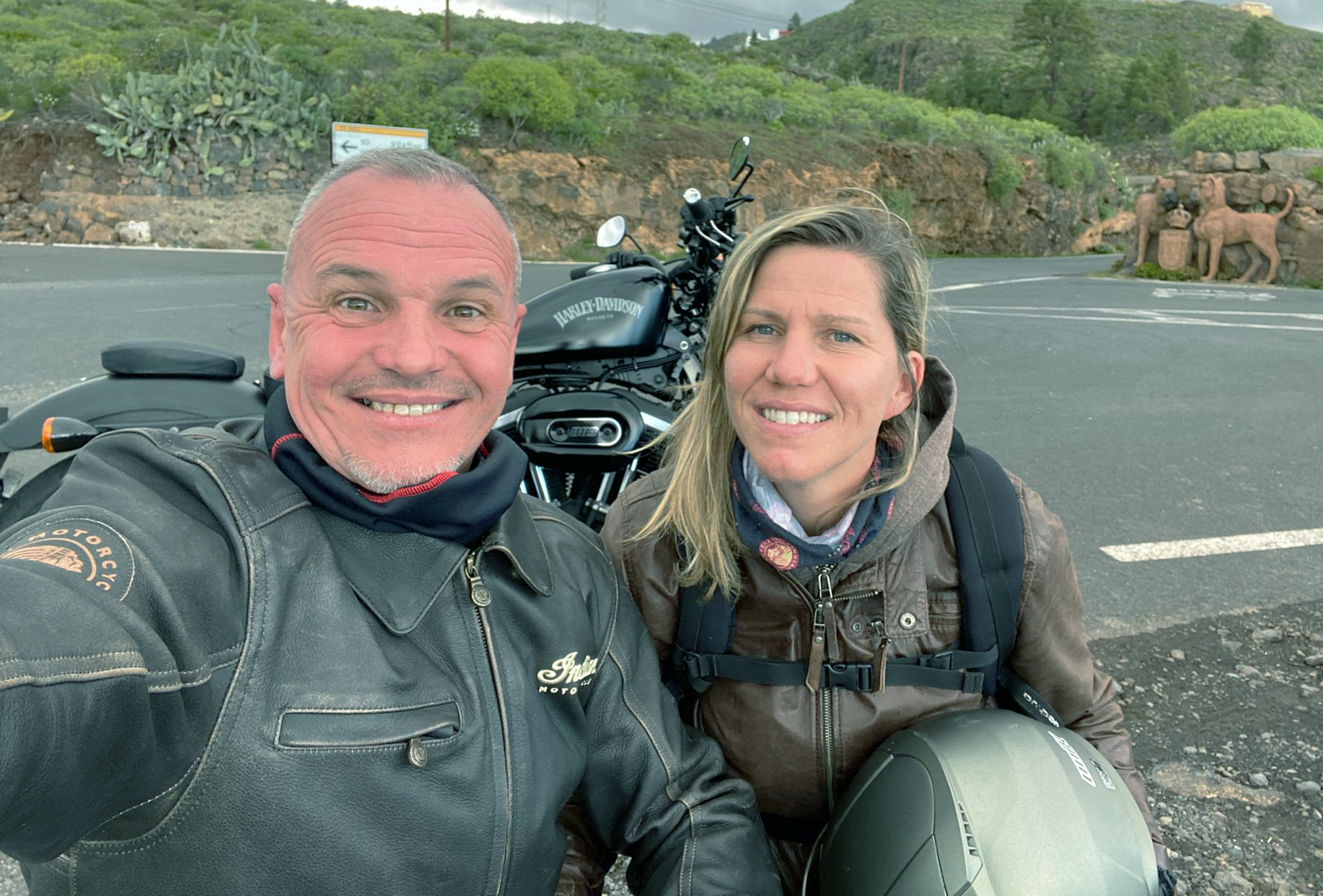 A man and a woman are posing for a picture in front of a motorcycle.