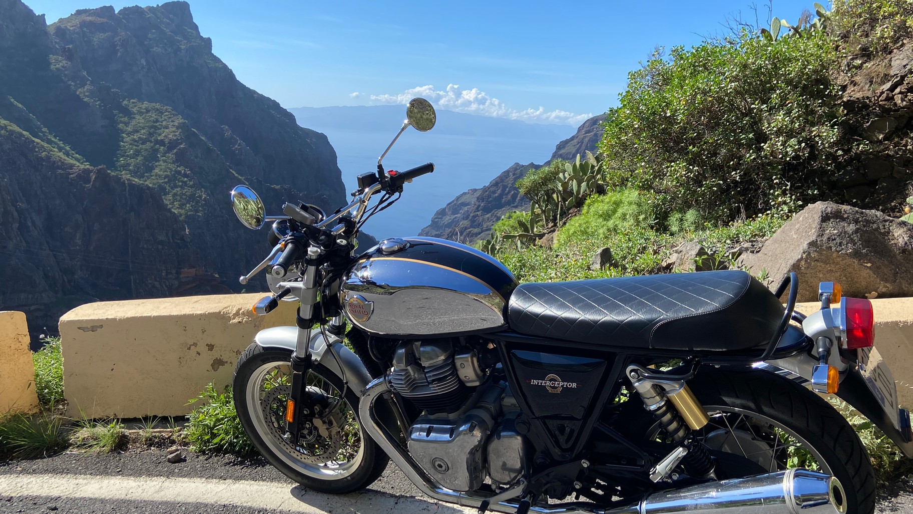 A motorcycle is parked on the side of a road next to a mountain.