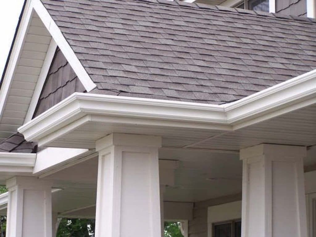 A close-up view of the white exterior trim, soffits, and roof shingles on the porch of a residential home.