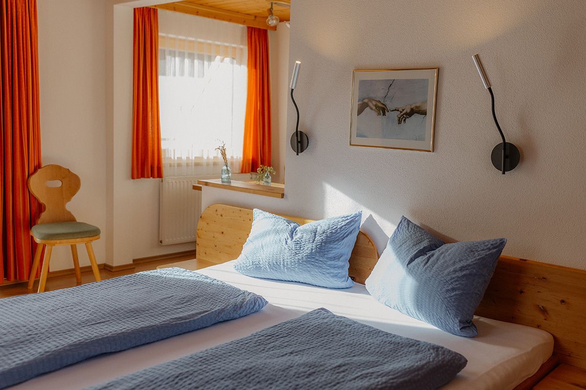 Hellblaues Doppelbett im gemütlichen Schlafzimmer eines Ferienhauses.
