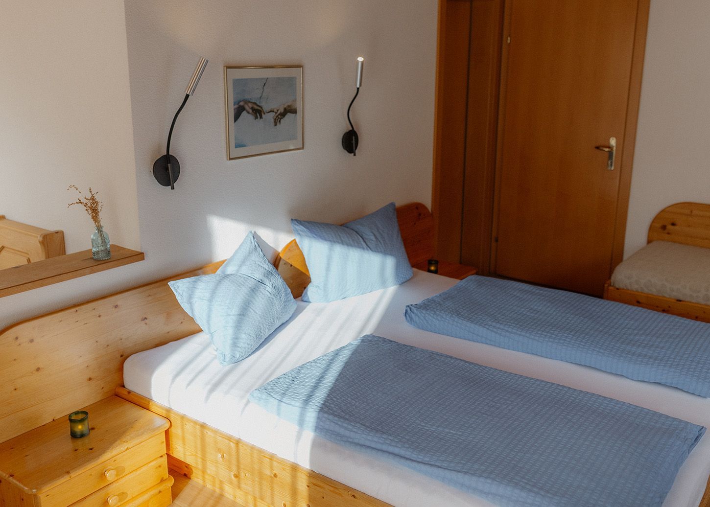 Hellblaues Doppelbett im gemütlichen Schlafzimmer eines Ferienhauses.
