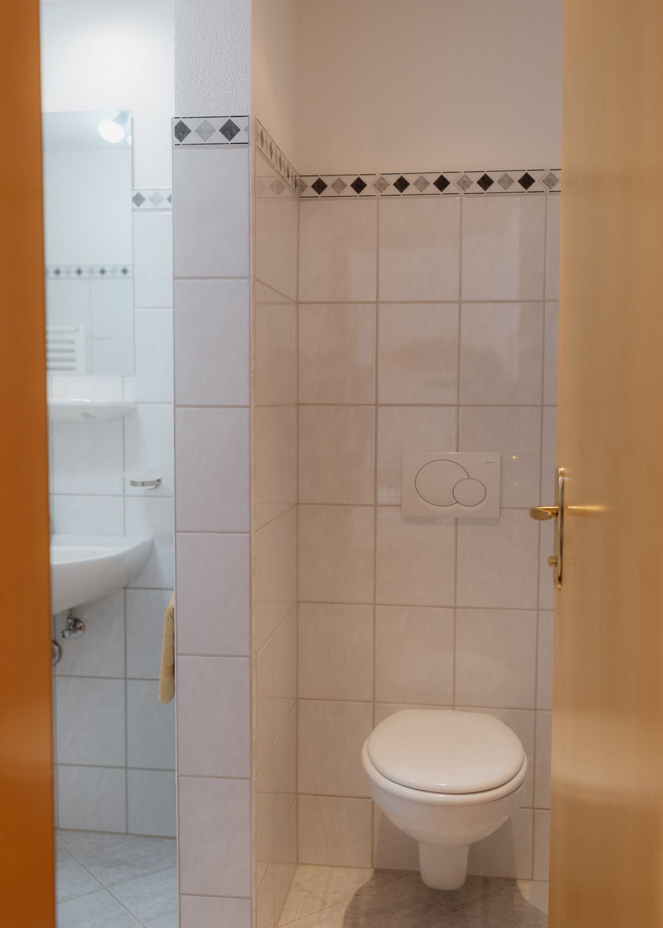 Hell gefliestes Badezimmer mit einer modernen Runddusche aus Glas und einem weißen Waschbecken mit verchromten Armaturen.
