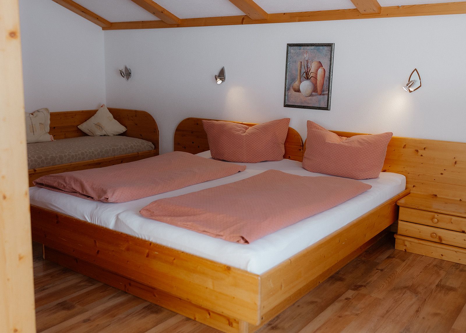 Hell eingerichtetes Schlafzimmer im Landhausstil mit Holz-Doppelbett, gemütlicher Bettwäsche in Altrosa 