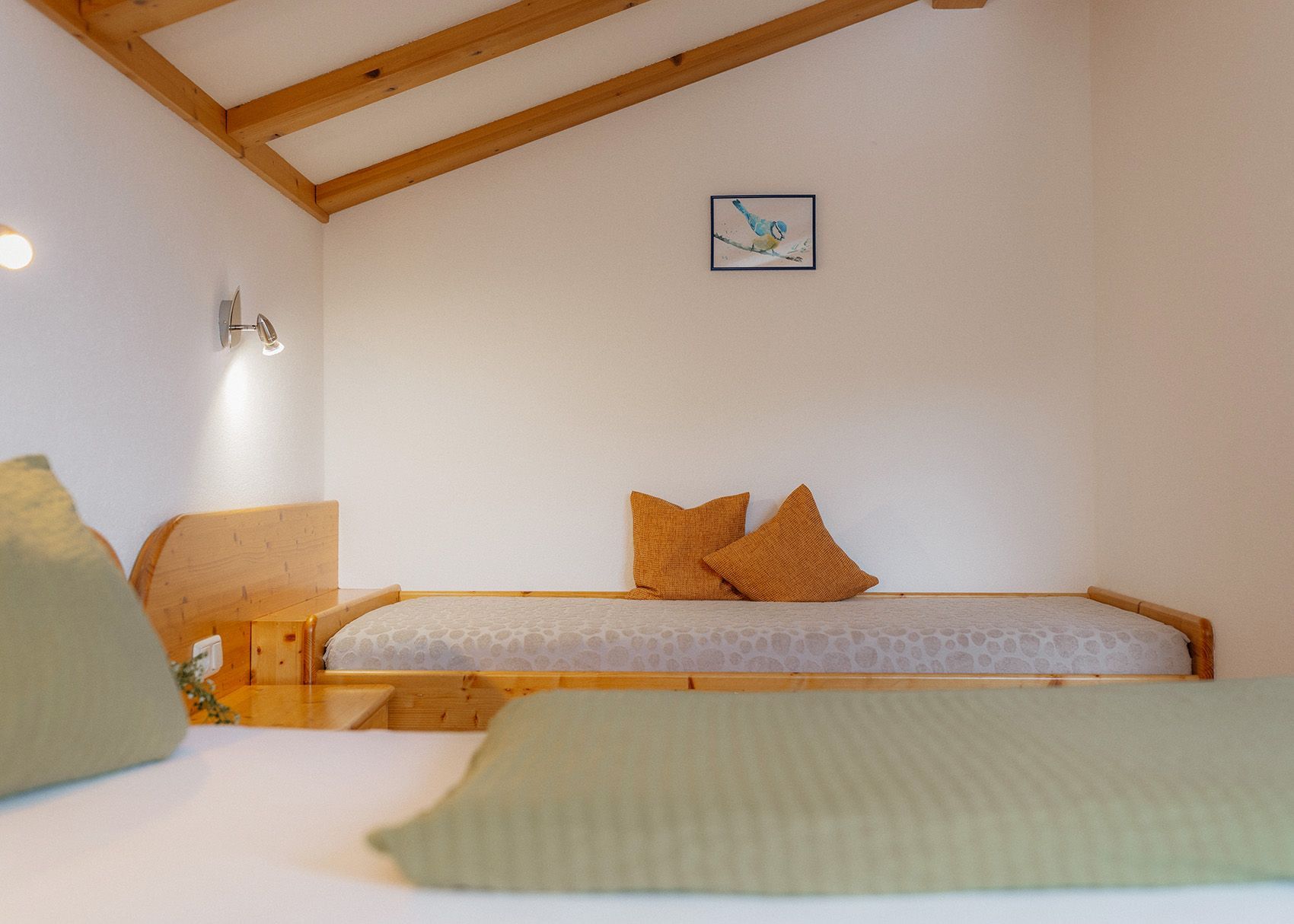 Hell eingerichtetes Schlafzimmer mit einer gemütlicher Dachschräge und Holz
balken