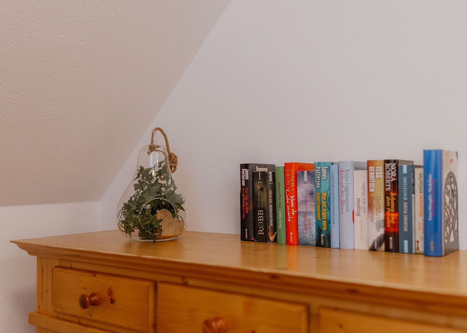 Rustikale Holzkommode aus Massivholz, bestückt mit einer Reihe von Büchern für Gäste und einer dekorativen Glasvase