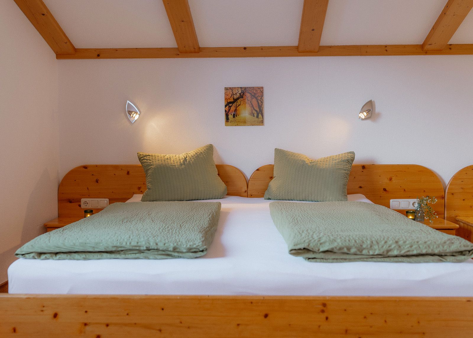 Gemütliches Schlafzimmer mit einem großen Doppelbett aus Massivholz und sichtbaren Deckenbalken an der Dachschräge.