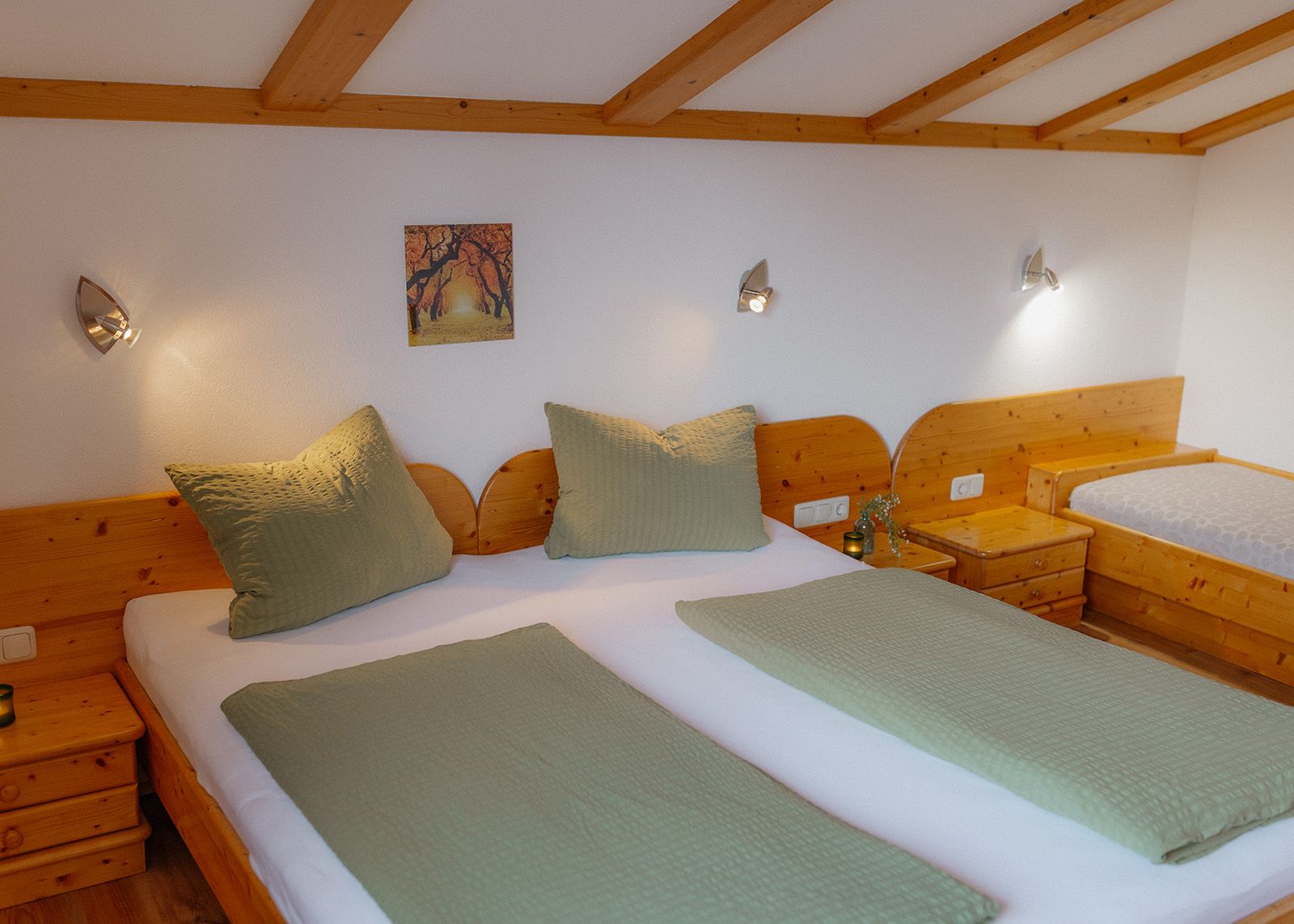 Gemütliches Schlafzimmer mit einem großen Doppelbett aus Massivholz, salbeigrüner Bettwäsche