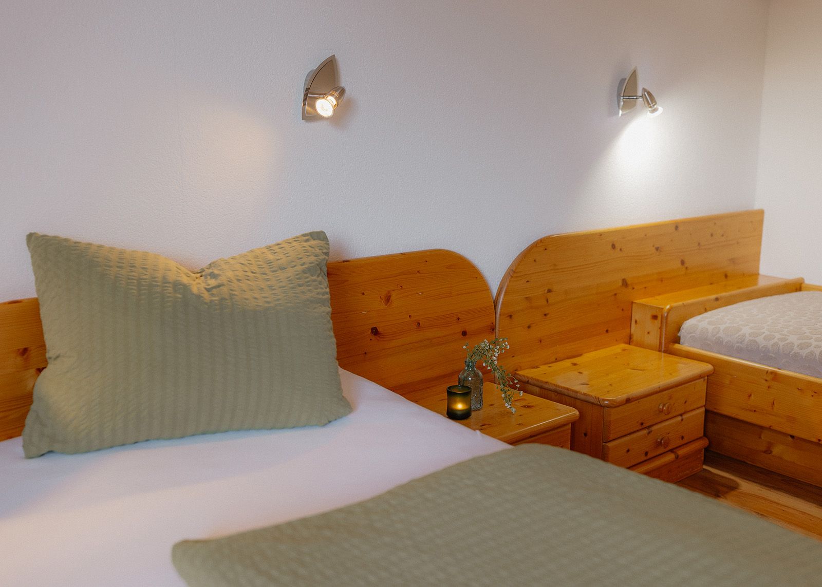 Gemütliches Schlafzimmer im Landhausstil mit einem großen Doppelbett aus Massivholz, salbeigrüner Bettwäsche