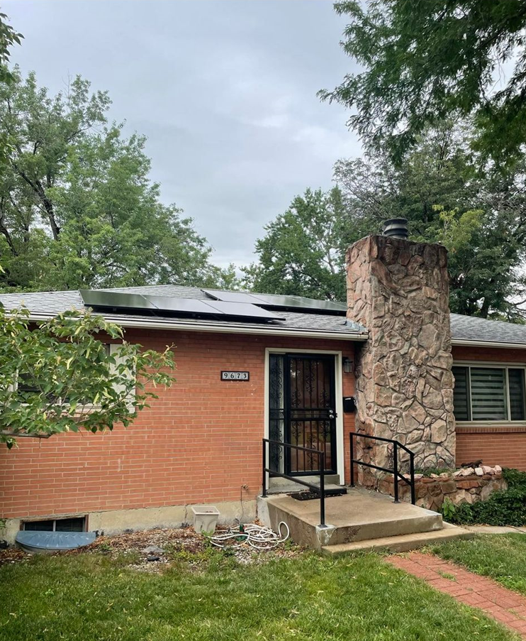 A brick house with a stone chimney and solar panels on the roof.