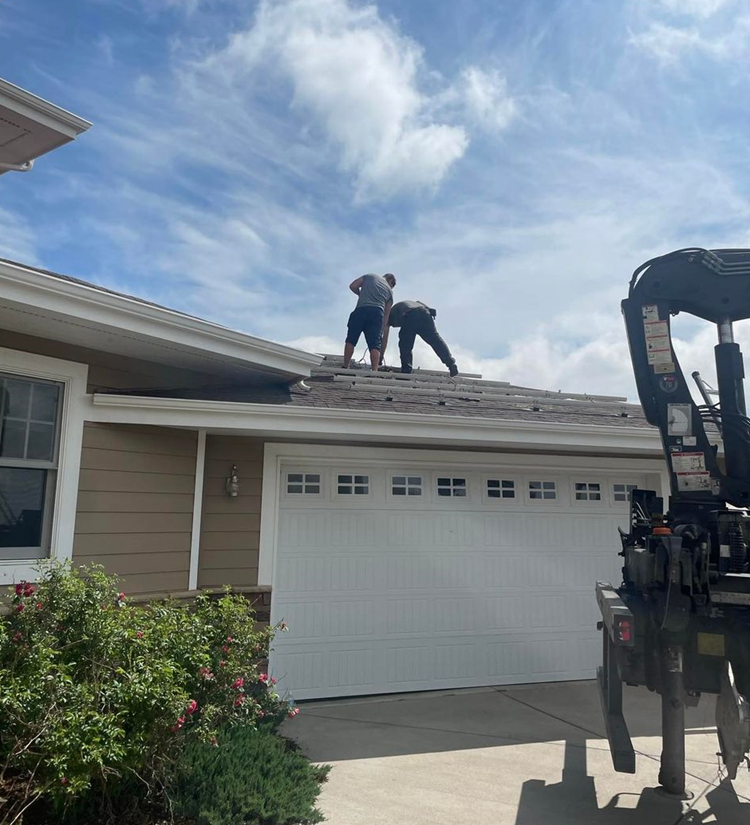 Two men are working on the roof of a house.