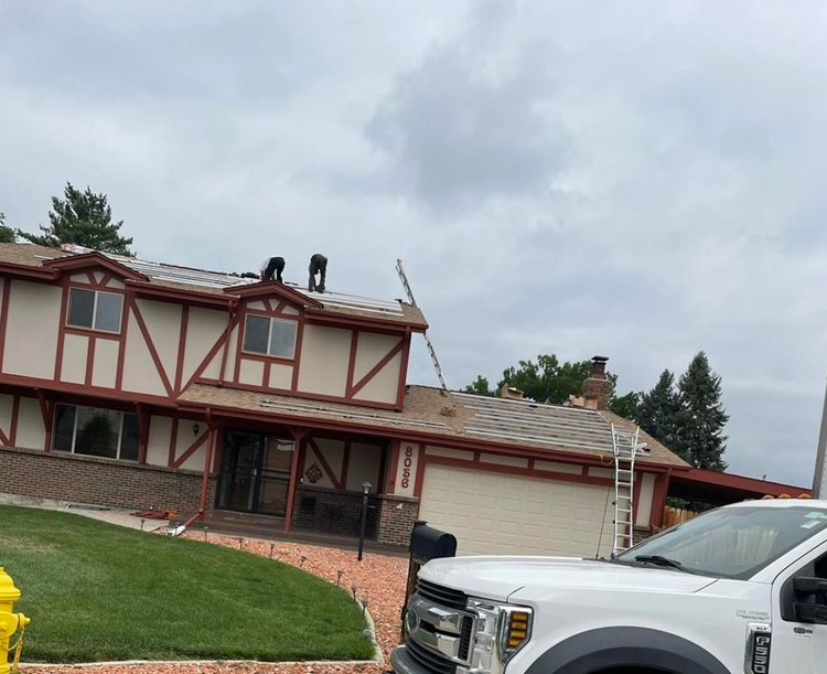 A white truck is parked in front of a house under construction.