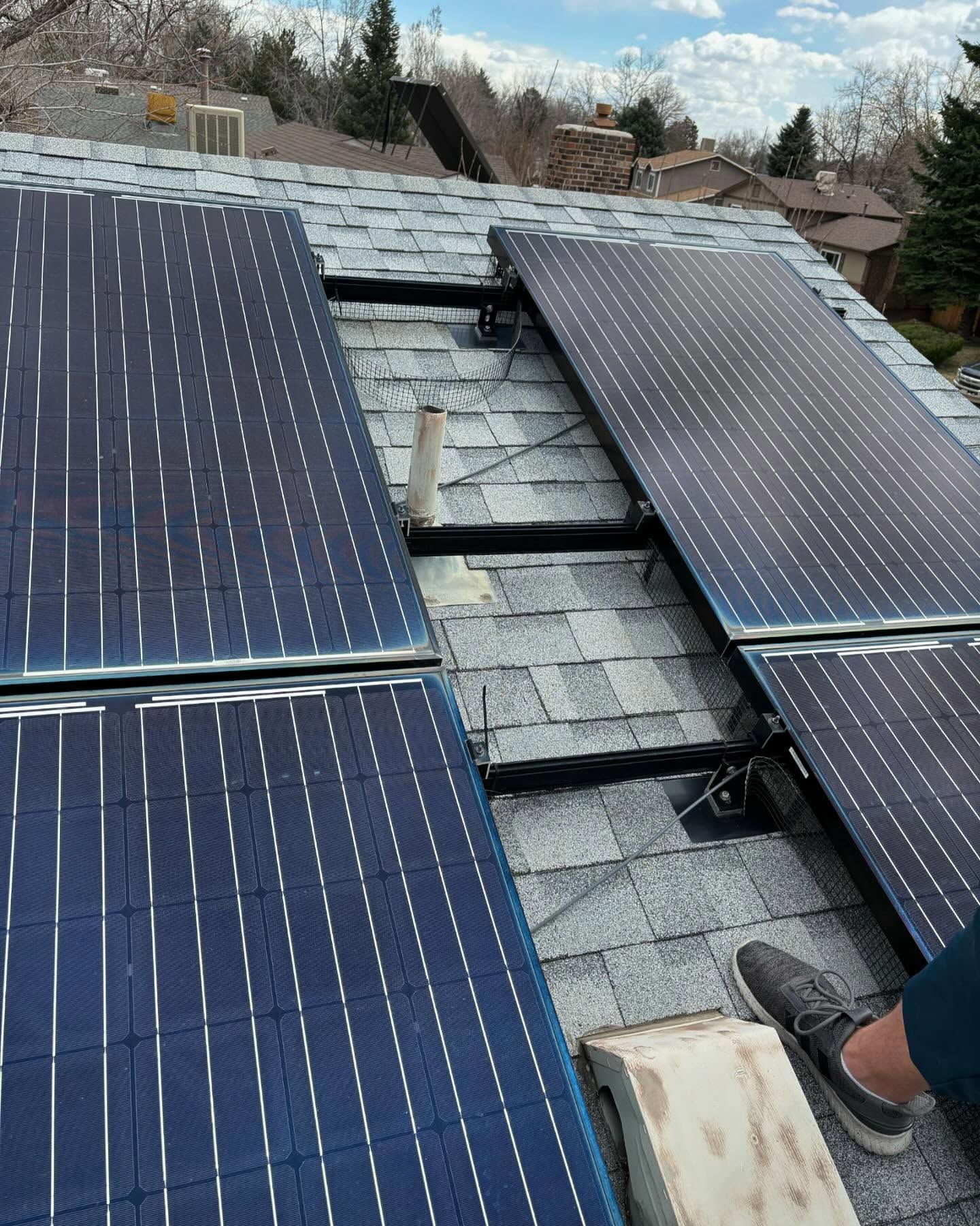A person is installing solar panels on the roof of a house.