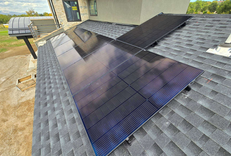 Solar panels installed on a dark gray shingled roof of a house.