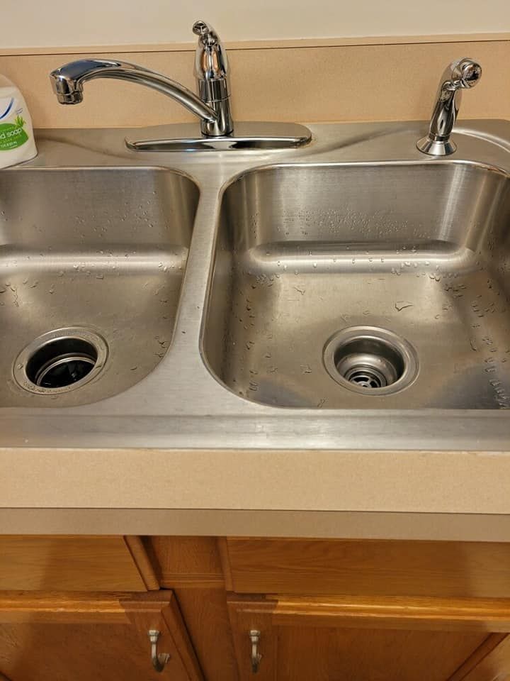 Stainless steel double kitchen sink with chrome faucet and cabinet below.