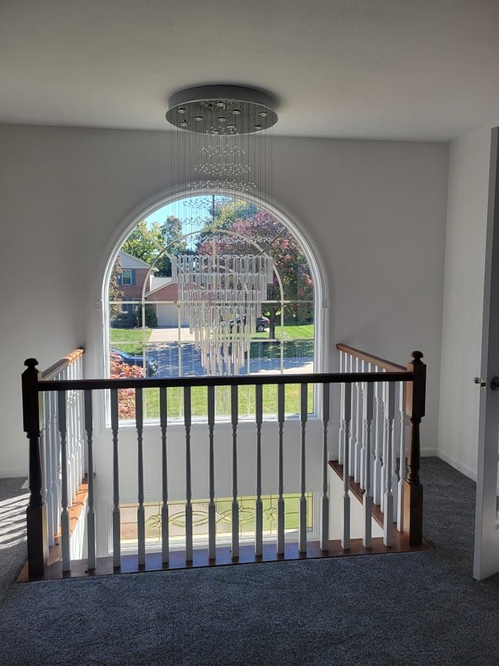Interior landing with black railing and arched window overlooking a courtyard