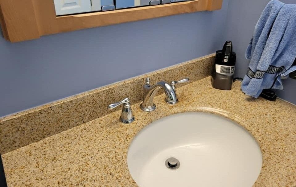 Bathroom sink with granite countertop, silver faucet, and blue wall.