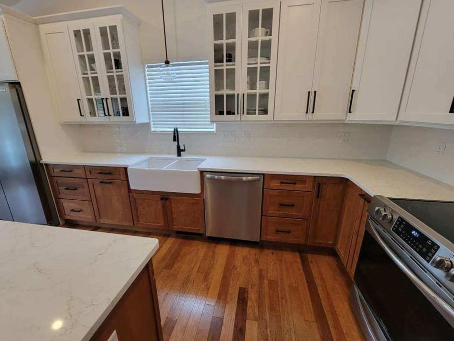 Kitchen with white countertops, brown cabinets, stainless steel appliances, and hardwood floors.