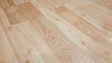 Light-colored wooden floor planks arranged diagonally, showing wood grain details.