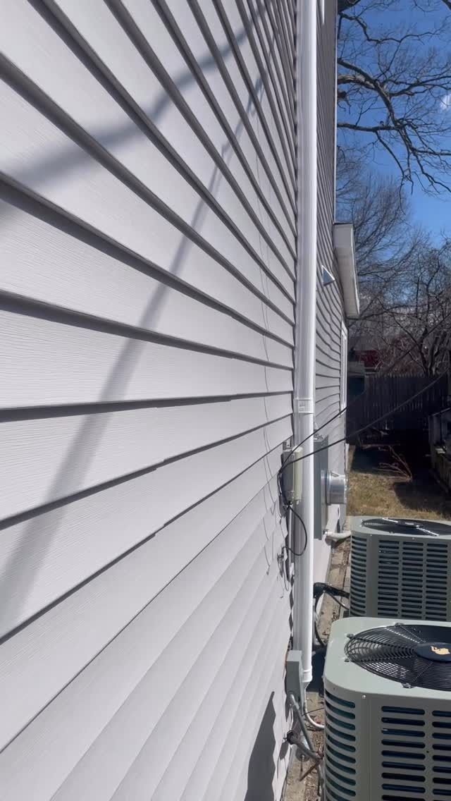White vinyl house siding beside outdoor air conditioner units and a narrow side yard.