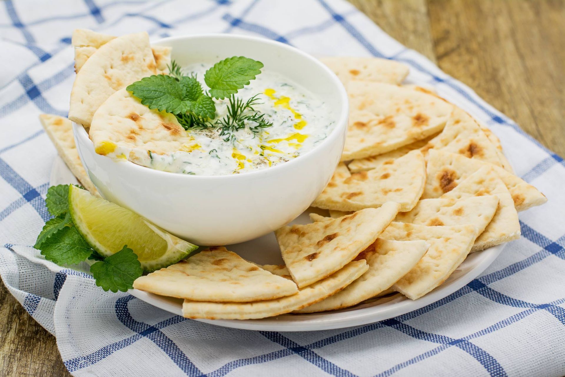 There is a bowl of dip on a plate with pita bread.