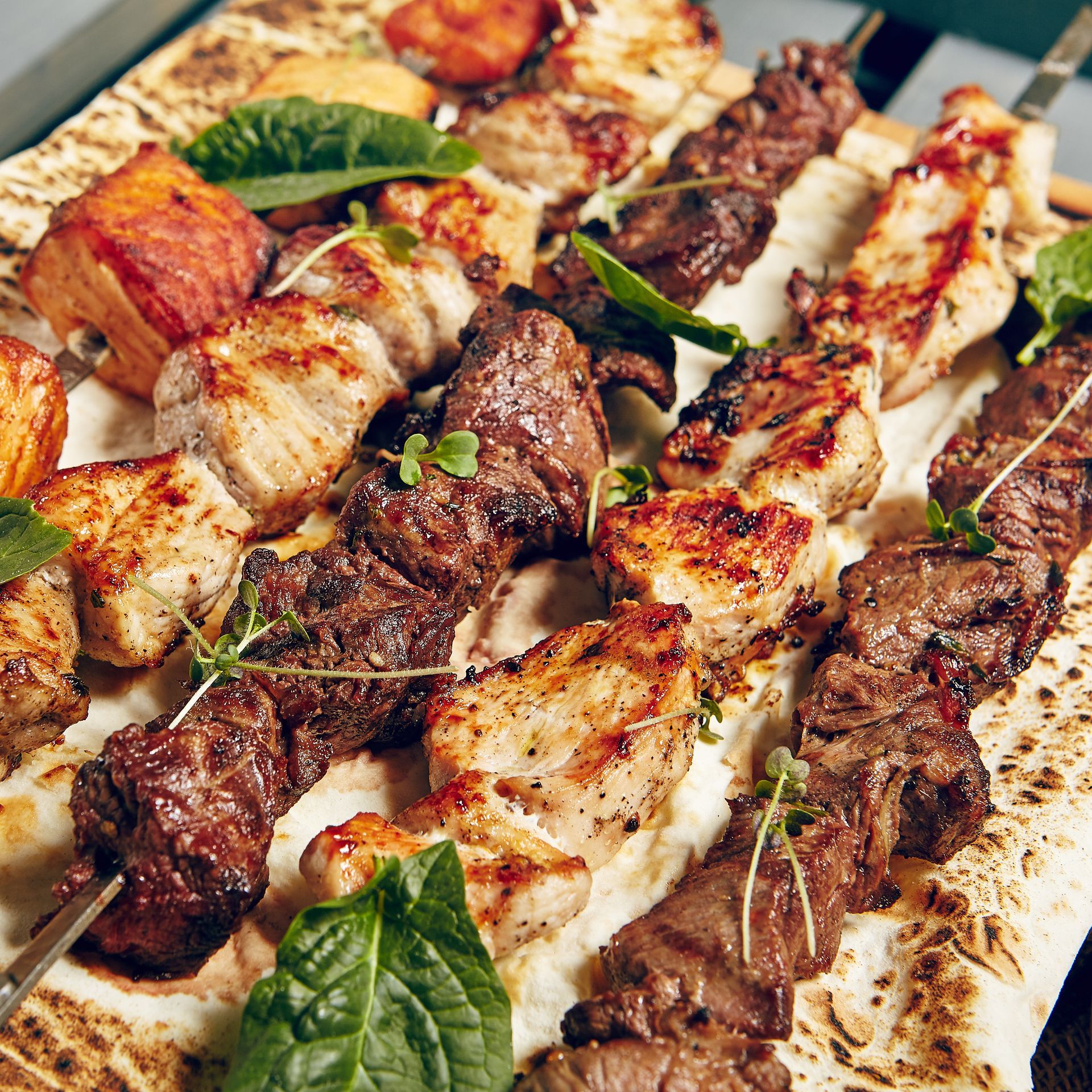 There are many different types of meat on skewers on a plate.