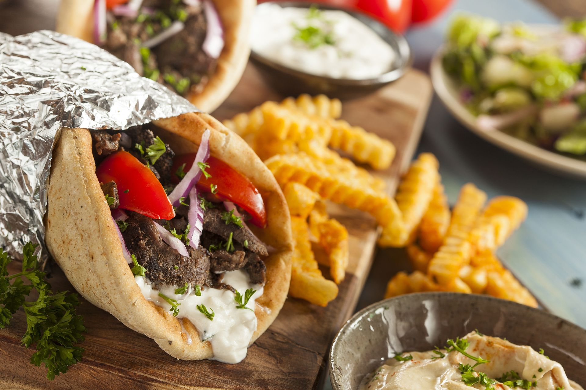 A gyro and french fries are on a wooden table.