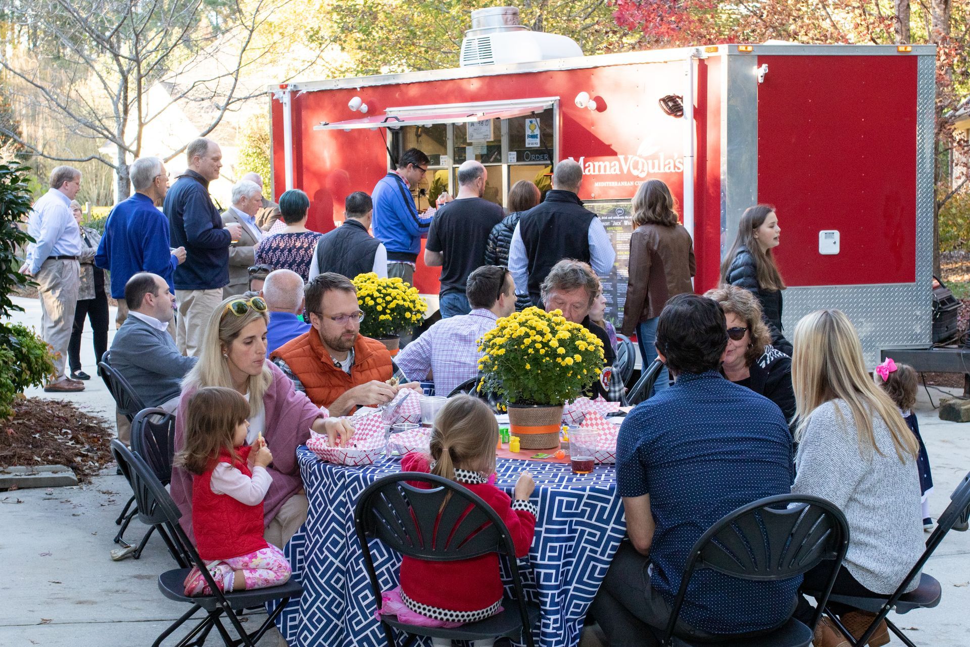A group of people are sitting at tables outside of a food truck.
