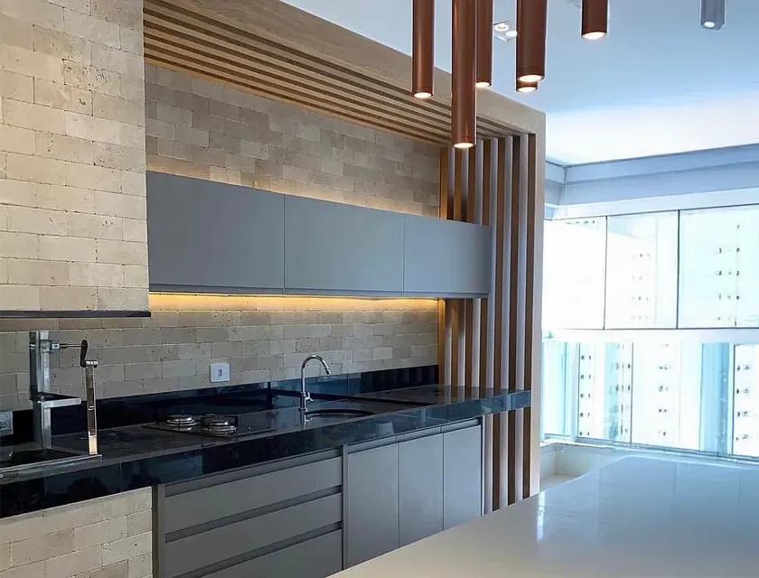 Cozinha moderna com backsplash de Travertino Artemano, armários cinza e luminárias pendentes de cobre.