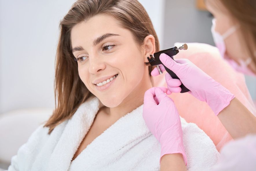 Una donna riceve un'applicazione di trucco alle labbra da un'artista con i guanti in un salone.