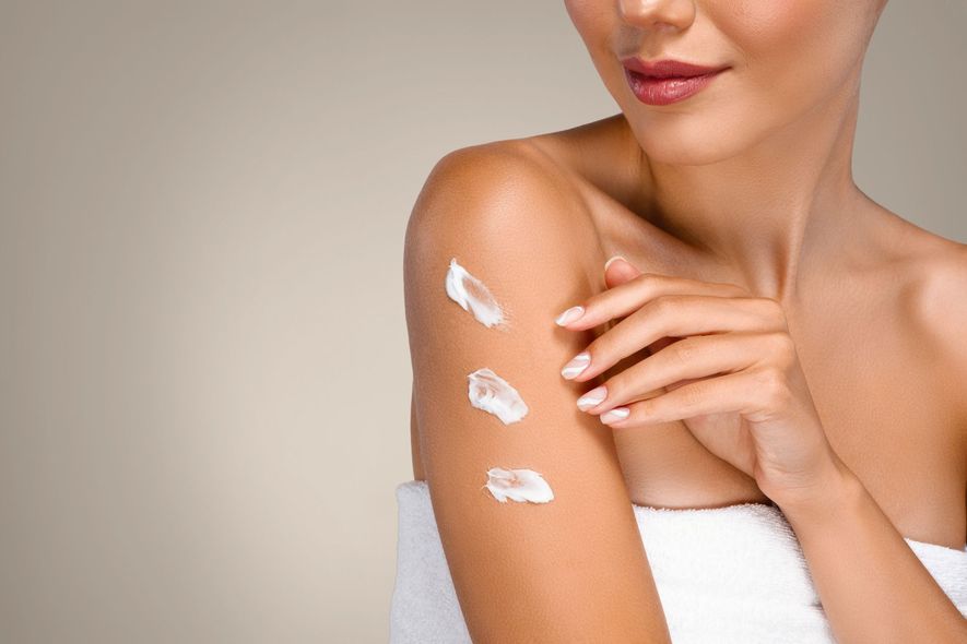Donna che applica la crema solare sulla spalla con tre passate di crema bianca