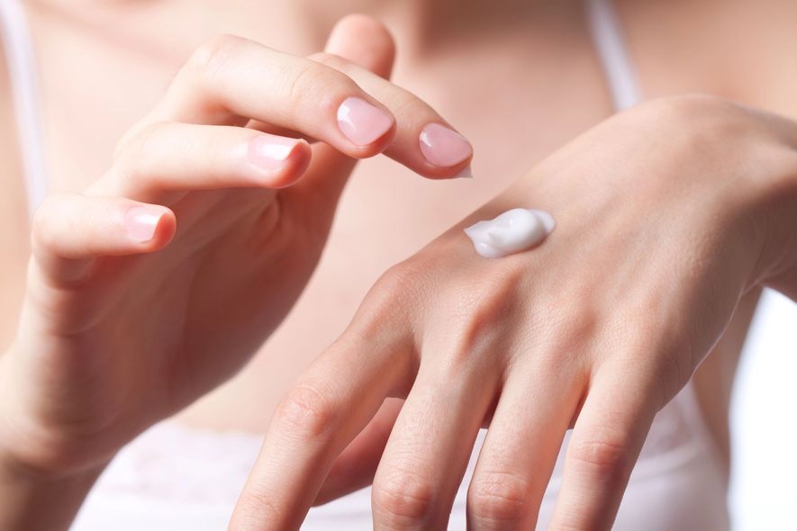 Applicazione manuale di crema bianca sul dorso della mano