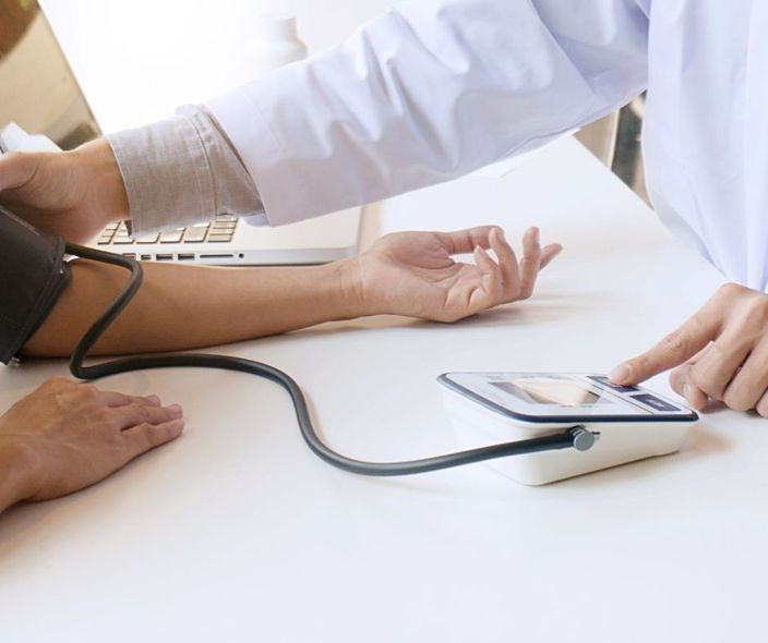 Misurazione della pressione sanguigna sul braccio di un paziente con un bracciale digitale in un contesto clinico.